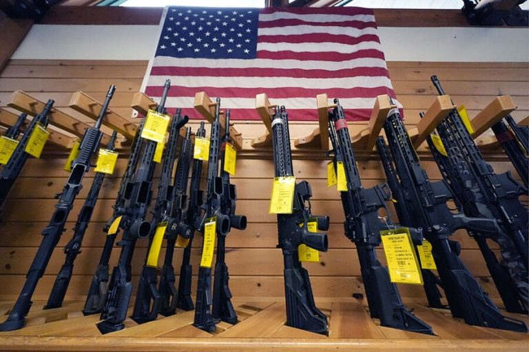 Display rack filled with semi-automatic rifles hanging beneath a large American flag