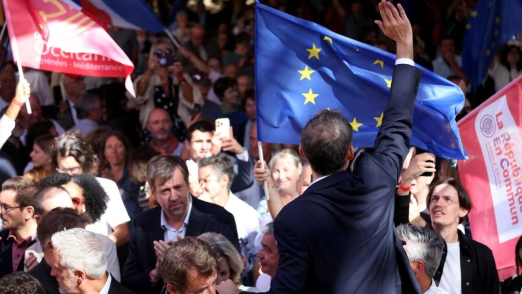 Politician waves to a cheering crowd holding an EU flag at a political gathering in France