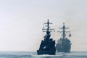 Israeli and American naval destroyers sailing in line on calm ocean waters