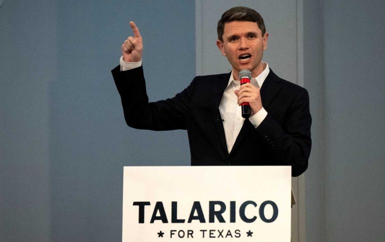 Democratic politician James Talarico speaking into a microphone and pointing his right index finger upward behind a podium that reads "Talarico For Texas".