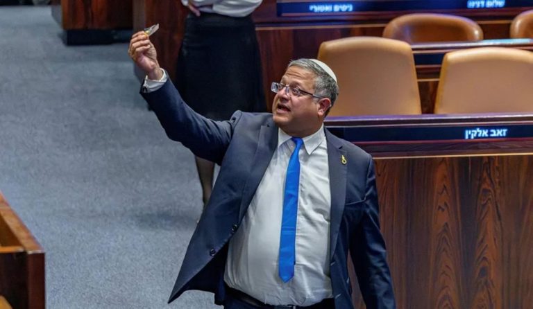 An Israeli politician holding up a small object inside the parliament chamber.
