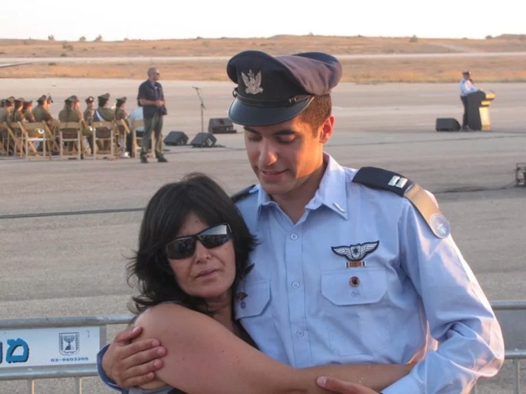 An Israeli Air Force officer in service uniform embracing a woman on an airfield tarmac
