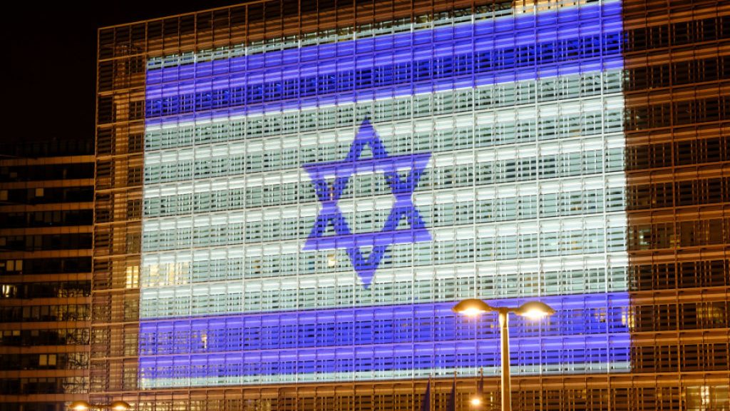 Israeli flag projected onto the glass exterior facade of the European Commission Berlaymont building at night