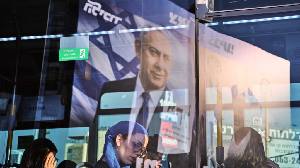 Commuters on a public transit bus with a political campaign poster of Benjamin Netanyahu visible in the window reflection.