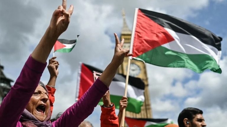 Protesters holding Palestinian flags and gesturing peace signs near Big Ben in London
