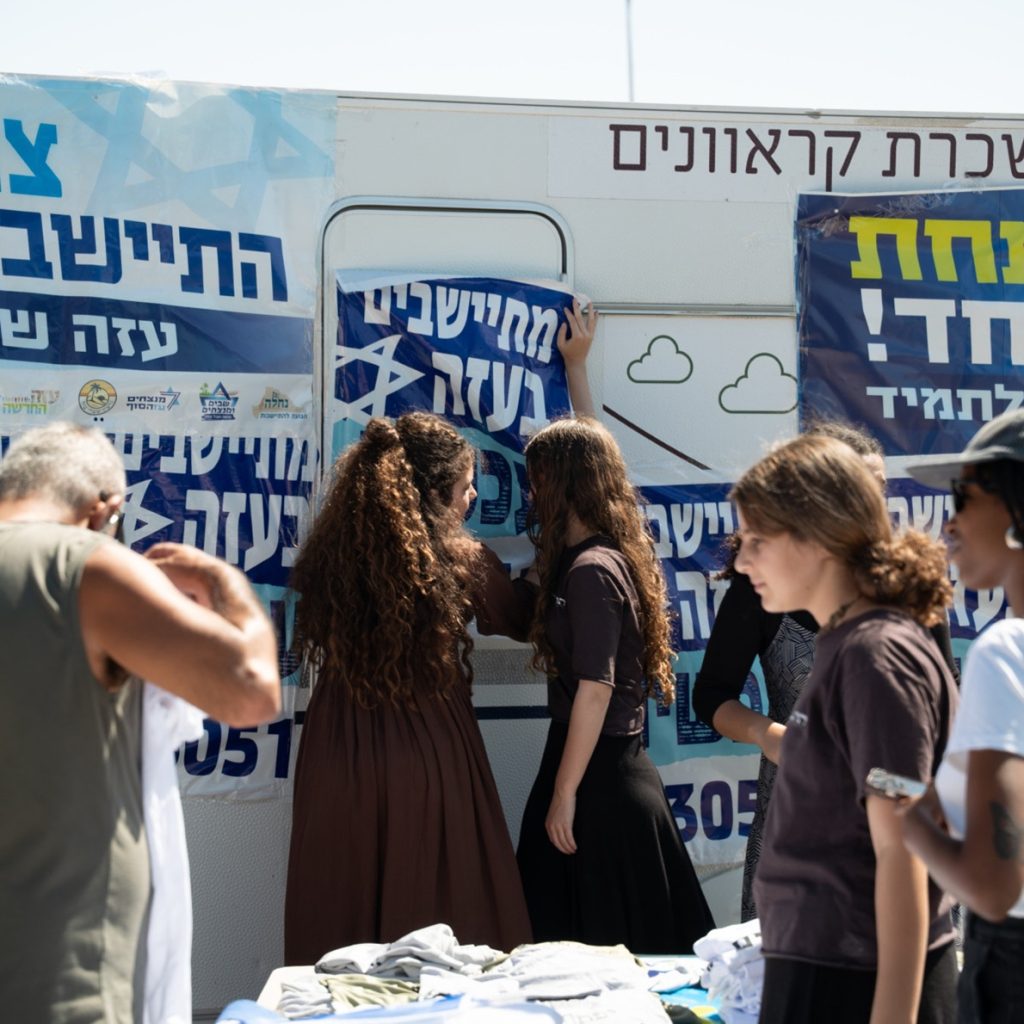 Israeli activists gathered around an information trailer decorated with settlement campaign banners.