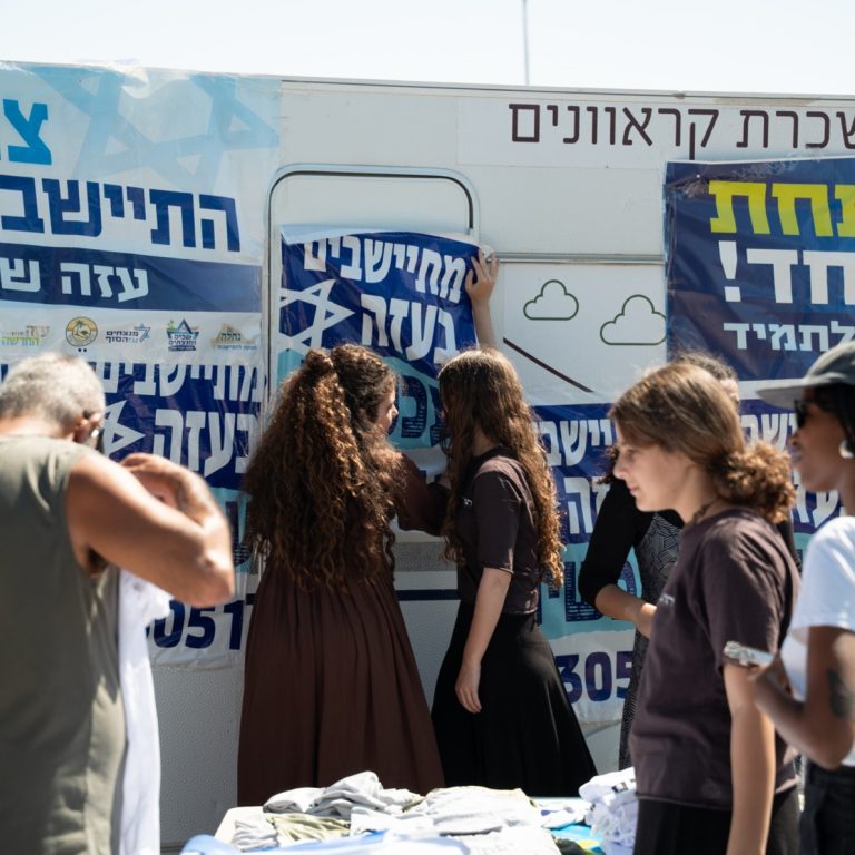 Israeli activists gathered around an information trailer decorated with settlement campaign banners.