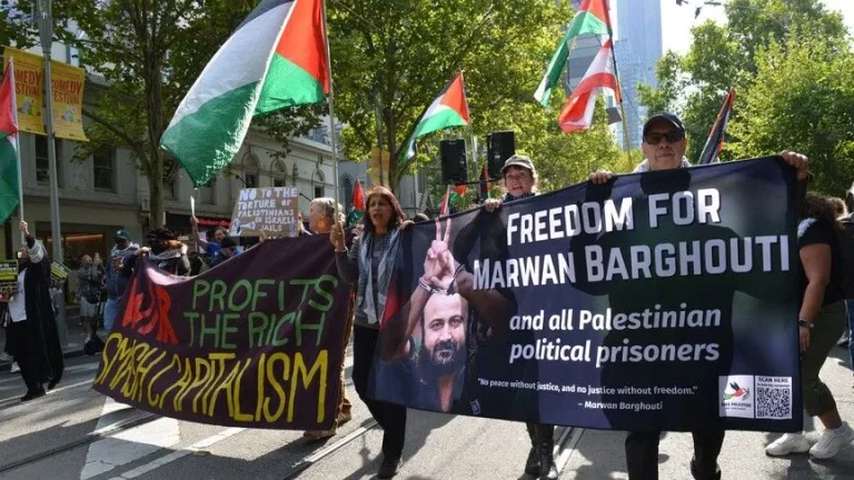 Protesters marching down a city street holding a large banner demanding freedom for Marwan Barghouti and Palestinian political prisoners