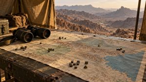 Military tactical map with miniature positioning markers laid out on an outdoor wooden table with binoculars overlooking rugged desert hills.