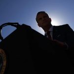 Silhouette of an official speaking from behind a podium bearing the Seal of the President of the United States