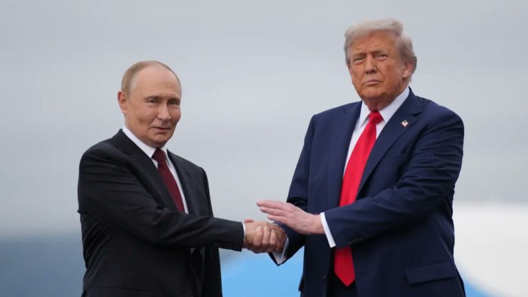 Vladimir Putin and Donald Trump shaking hands outdoors in suits and ties.