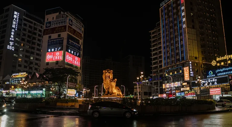Sihanoukville Golden Lions roundabout at night surrounded by illuminated casinos and high-rise commercial buildings