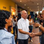 Politicians shaking hands with local residents on a bustling street in Miami.