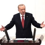 Turkish President Recep Tayyip Erdoğan gesturing from behind a rostrum during a speech