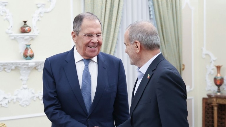 Russian Foreign Minister Sergey Lavrov shaking hands and smiling with Iranian Foreign Minister Abbas Araghchi